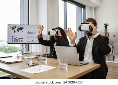 Business professionals using virtual reality headsets during meeting in modern office setting. Diverse team exploring VR technology to analyze data and visual representations on screen. - Powered by Shutterstock