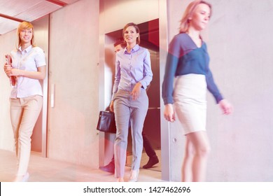 Business professionals walking out of elevator in office