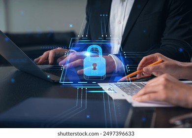 Business professionals working on a laptop and documents with a digital padlock icon overlay. The concept of data security and protection in a business environment - Powered by Shutterstock