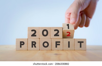 Business profit plan concept in 2022 . Build a profit and financial plan. Hand flip wooden cubes 2021 to 2022 with text "PROFIT" on white background and copy space. Business performance target in 2022 - Shutterstock ID 2086330882