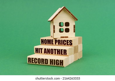 Business And Real Estate Concept. On A Green Surface, The House Stands On Blocks. Blocks With The Inscription - Home Prices Hit Another Record High