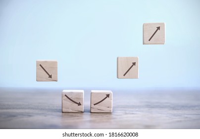 Business recovery concept; building blocks mid air with arrows first heading down then in an upwards direction