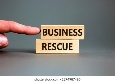 Business rescue symbol. Concept words Business rescue on wooden blocks on a beautiful grey table grey background. Businessman hand. Business rescue and support concept. Copy space.