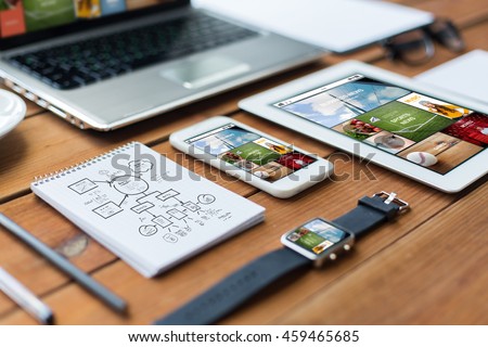 business, responsive design and technology concept - close up of on laptop computer, tablet pc, notebook and smartphone with scheme and internet news application on wooden table