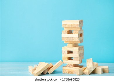 Business Risk Concept With Wood Jenga Game. Wooden Blocks On Blue Background