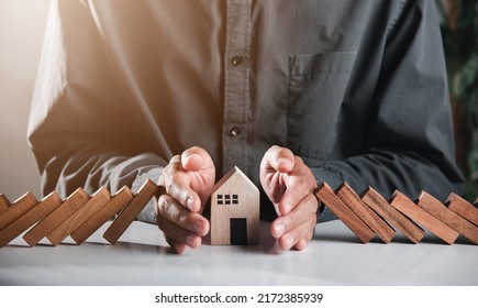 Business risk plan real estate protection. Man hand blocks wood block from many row falling wooden block like domino to house model, Insurance ideas to prevent loss concept - Powered by Shutterstock