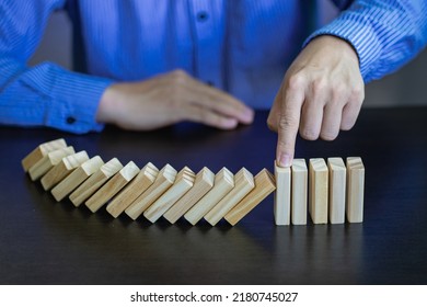 Business Risks and Strategies hand stop falling wooden block domino Consequences of falling blocks defense and development for security Prevention and problem solving concepts - Shutterstock ID 2180745027