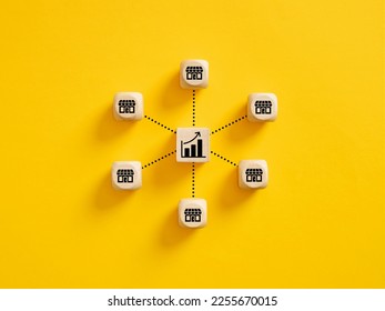Business sales growth. Expanding franchise stores and increasing profitability concept. Wooden cubes with store and ascending graph symbols linked with each other with lines. - Shutterstock ID 2255670015