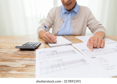 business, savings, annuity insurance, age and people concept - close up of senior woman with papers or bills and calculator writing at home
