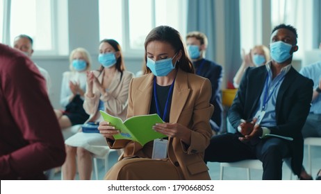 Business seminar. Quarantine. Attentive multi-ethnic corporate men and women with masks listening to business lecture presentation in conference meeting room. Social distancing.