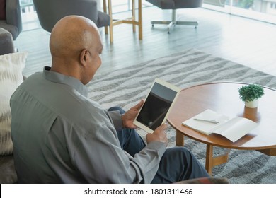 Business senior old elderly Black American man, African person working from home on table with tablet or laptop and blank screen on webcam video call conference in quarantine in corona virus pandemic.