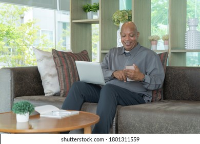 Business senior old elderly Black American man, African person using a smartphone or mobile phone in living room at home in technology device concept. Lifestyle people.