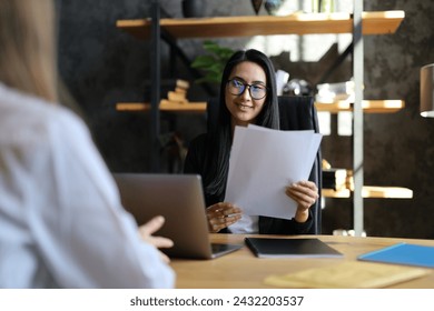 In a business setting, an Asian woman confidently conducts a recruitment interview, fostering a professional atmosphere. - Powered by Shutterstock