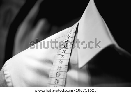 Business shirt tailoring on tailor shop mannequin with measure tape across neck 