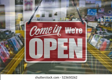 A business sign that says 'Come in We're Open' on a Music/Records store window.