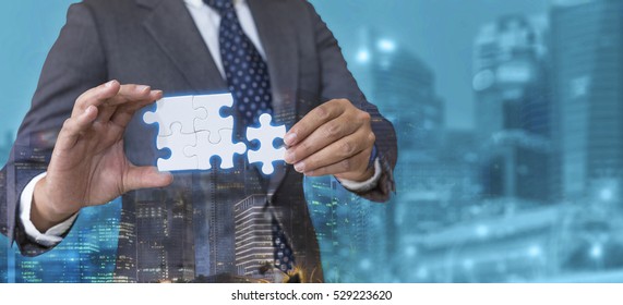 Business solutions, success and strategy concept. Businessman hand connecting jigsaw puzzle with cyan city background. Double exposure. - Shutterstock ID 529223620