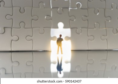 Business solutions, success and strategy concept. Miniature people: small businessman standing in front of the huge gate jigsaw puzzle. - Powered by Shutterstock