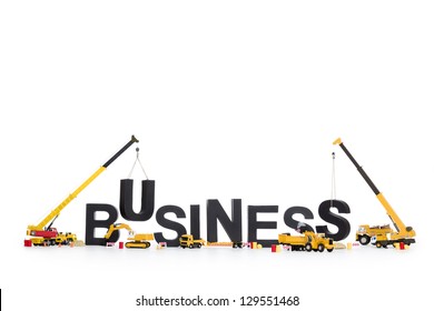 Business Start Up Concept: Black Alphabetic Letters Forming The Word Business Being Set Up By Group Of Construction Machines, Isolated On White Background.
