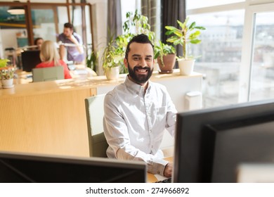 business, startup and people concept - happy businessman or creative male office worker with computer