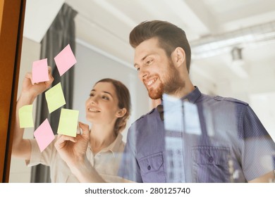 business, startup, planning, management and people concept - happy creative team writing on stickers at office glass board - Powered by Shutterstock