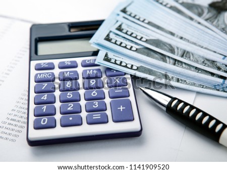 business still-life from a calculator and a bundle of banknotes 100 dollars close up