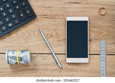 Business Still-life. Calculator And Mobile Phone, Pen And Money, Ruler And Ring On An Old Wooden Table