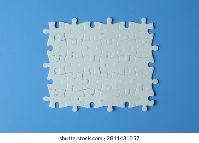 Business strategy and problem solving concept. Top view of assembled blank white jigsaw puzzle on blue background. Teamwork, successful solution, unity and integration copy space.