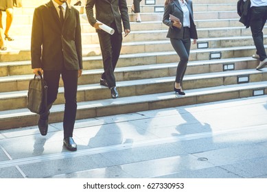 Business Street In Big City.After Office Work.In Front Of Corporate Building.Businessman Walking Quick Steps.Some Person Hold Business Briefcase Go Down From Stairs.Some Person Commute To Home By Car.