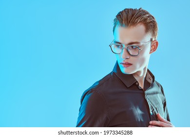 Business style. Portrait of a handsome young man in elegant glasses on a blue background with opy space. Men's accessories, optics. 