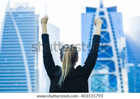 Business success - Celebrating businesswoman overlooking the city center high-rises.