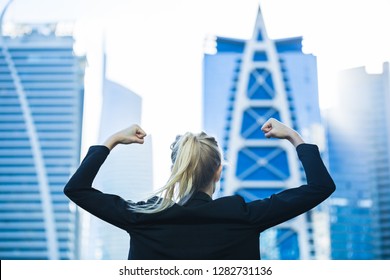Business success! Celebrating strong confident businesswoman flexing against a city high-rise view.