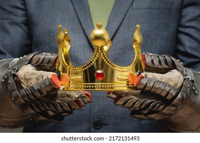 Business Success Concept. Businessman In The Plate Armor Mittens Holds A Golden Crown Close Up. Authority Power.