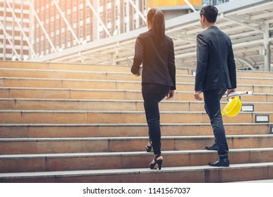 Business and success concept. Persons Back view walking toward successful after meeting. Legs of Engineer and Businesswoman Walk up stair way together to progress work in office.