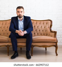 Business And Success Concept - Portrait Of Handsome Bearded Man Sitting On Vintage Sofa