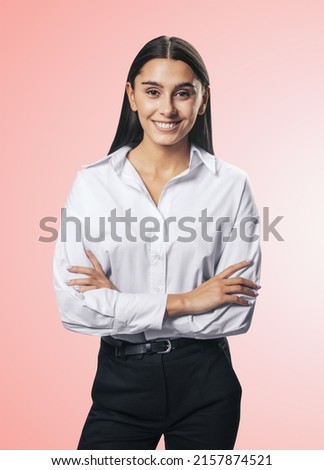 Business success concept with young smiling woman folding her hands in white shirt and black trousers on abstract light pink background, close up, isolated