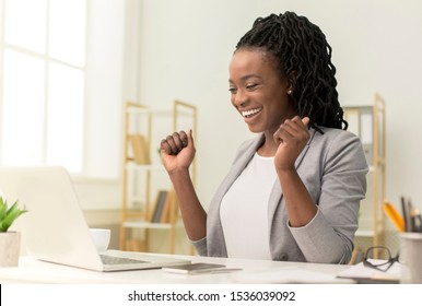 Business Success. Excited Black Businesswoman Sitting At Laptop Shaking Fists In Modern Office. - Powered by Shutterstock