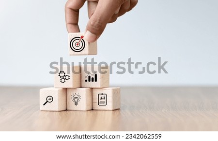Business success goals Concept. Hand holding target board which printing on wooden cube block for creative and set up business objective target goal concept, blocks to create ideas, set target.