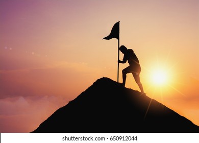 business, success, leadership, achievement and people concept - silhouette of businessman with flag on mountain top over sky and sun light background