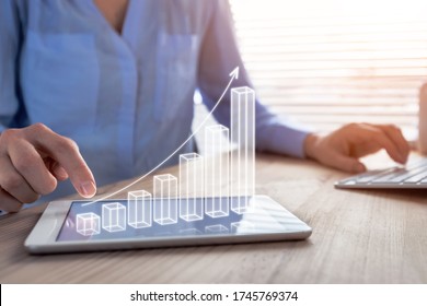 Business success and profit displayed by 3d growing bar chart, successful businesswoman working in bright office with computer and digital tablet, manager increasing revenue