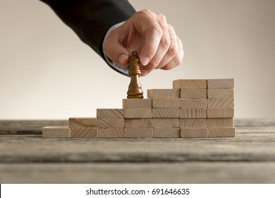 Business success and promotion concept with a businessman moving the queen piece up a series of steps formed by building blocks. - Powered by Shutterstock