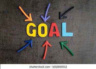 Business success strategy goals concept, colorful wooden alphabets GOAL at the center with pointing arrow on black chalkboard cement wall.