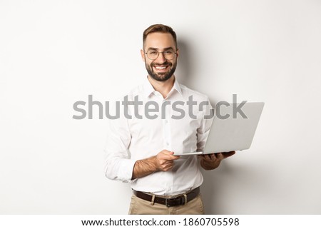 Business. Sucessful businessman working with laptop, using computer and smiling, standing over white background