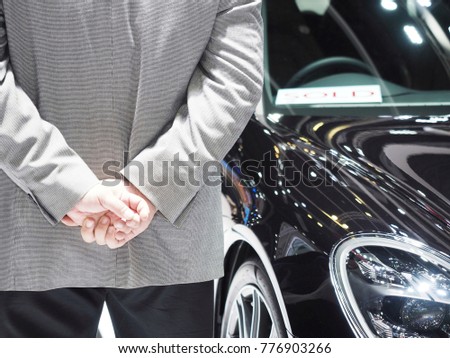 business suit man hold hand behind back and sold sport super car in showroom