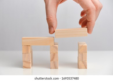 Business Takeover Concept. Hand Holds Wooden Blocks On A White Background. Close Up.