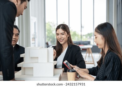 Business team analyzes architectural models in a modern office setting, indicating teamwork and project development. - Powered by Shutterstock