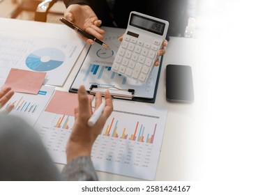 Business team analyzing documents, graphs, and data with a laptop, tablet, and smartphone. Collaboration, strategy, and success in a modern office.