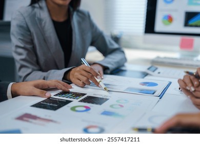 Business team analyzing financial data using charts and graphs, discussing strategies and performance in a collaborative office environment - Powered by Shutterstock