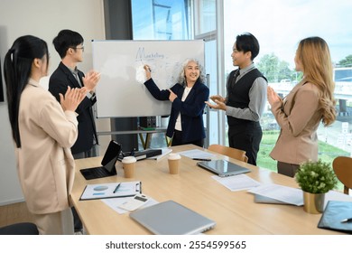 Business team applauding senior female leader during marketing strategy presentation - Powered by Shutterstock