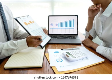 Business Team In Casual Style Have Small Meeting In The Office Talk About  Analyses Chart Graph Marketing Plan With Computer Laptop Calculator.