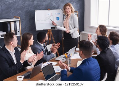 Business team congratulating successful female manager with applause at conference meeting